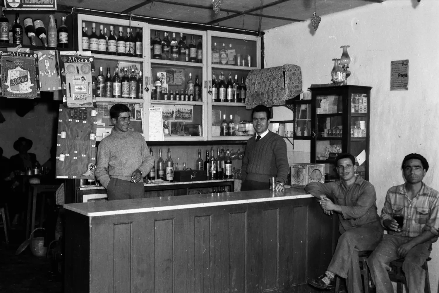 Fotografia antiga de um café em Tavira, com pessoas junto ao balcão